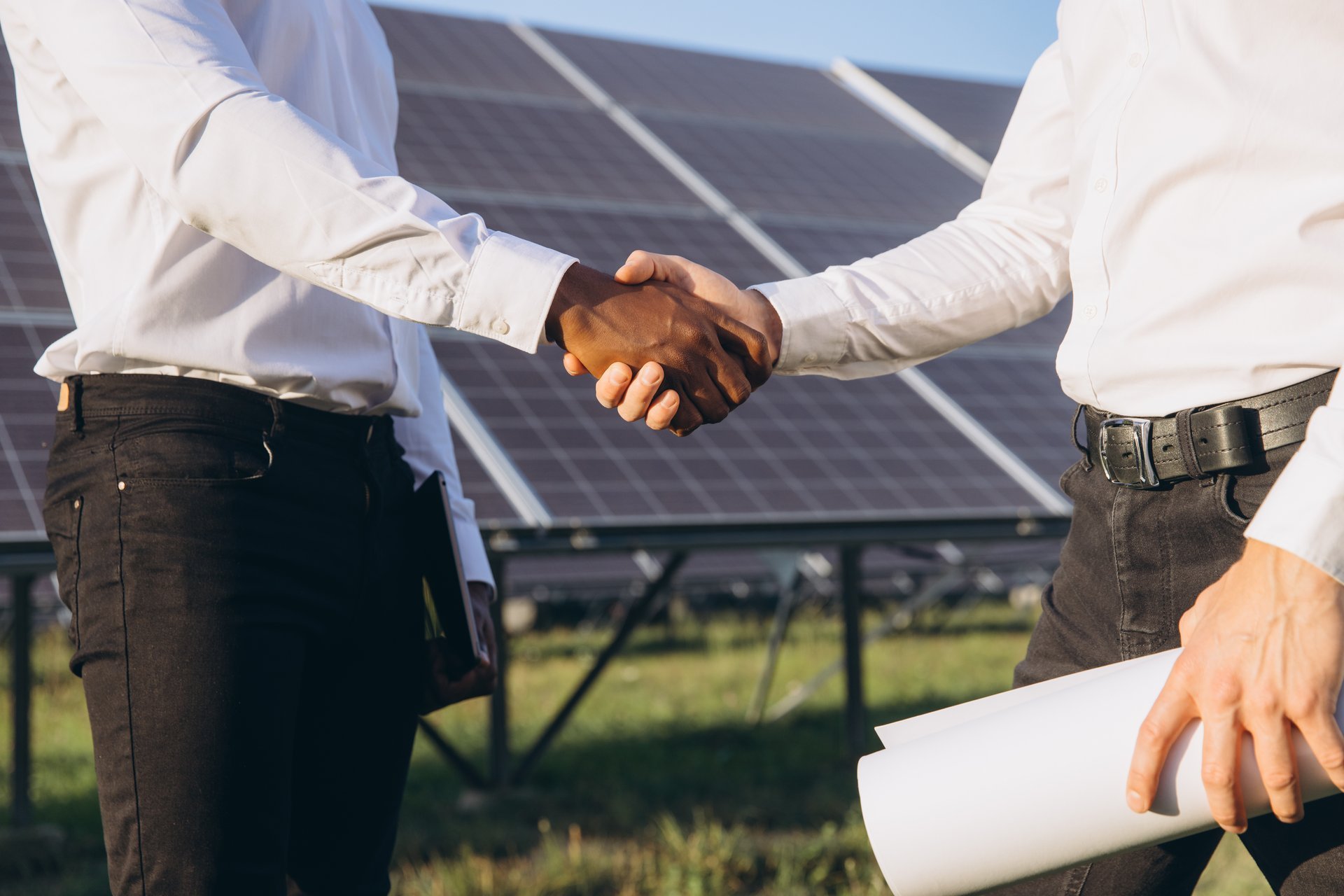 Two businessmen shake hands at a solar power plant